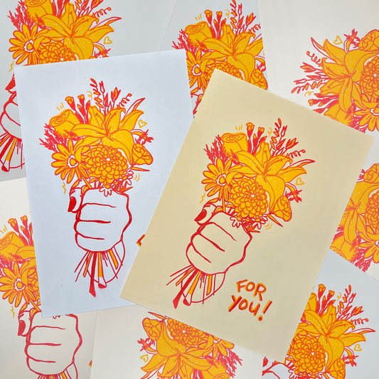 Photo showing the “For You” hand illustrated riso print of a bouquet of flowers in a fist with red and yellow risograph ink on both white and tan colored paper.