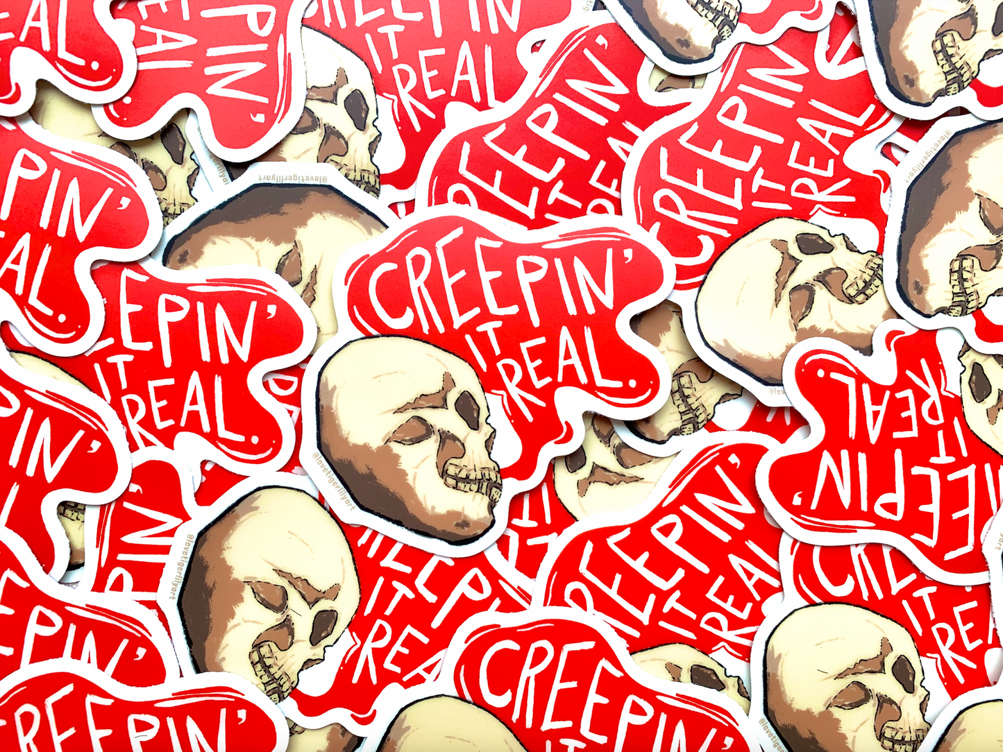 Multiple Glow in the Dark Creepin It Real stickers of an illustrated skull saying “Creepin It Real” in the daylight
