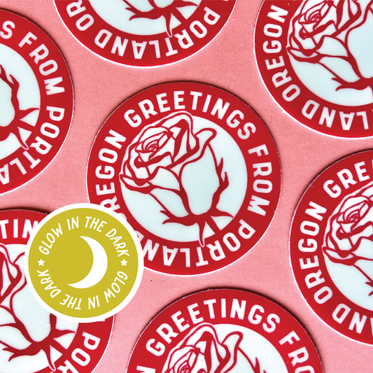 Round sticker with a red rose and white text saying "Greetings from Portland Oregon"