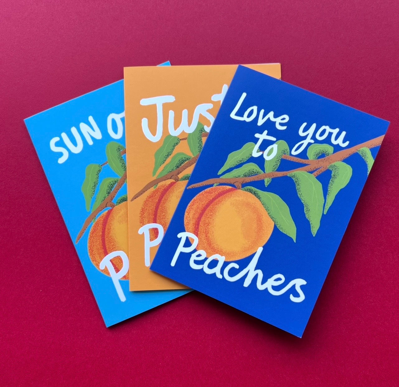 Three colorful greeting cards with peach illustrations and text on a red background