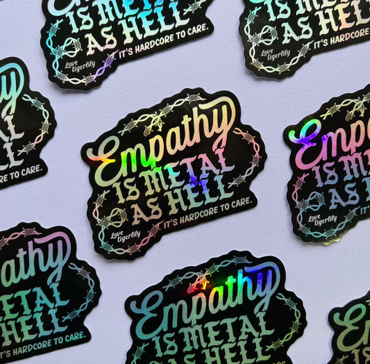 Holographic stickers with 'Empathy is metal as hell & it's hardcore to care' text design with barbed wire on a light purple background