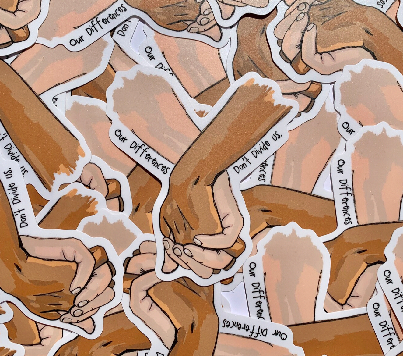 Illustrated sticker that has holding hands with words around them saying our difference doesn't divide us.