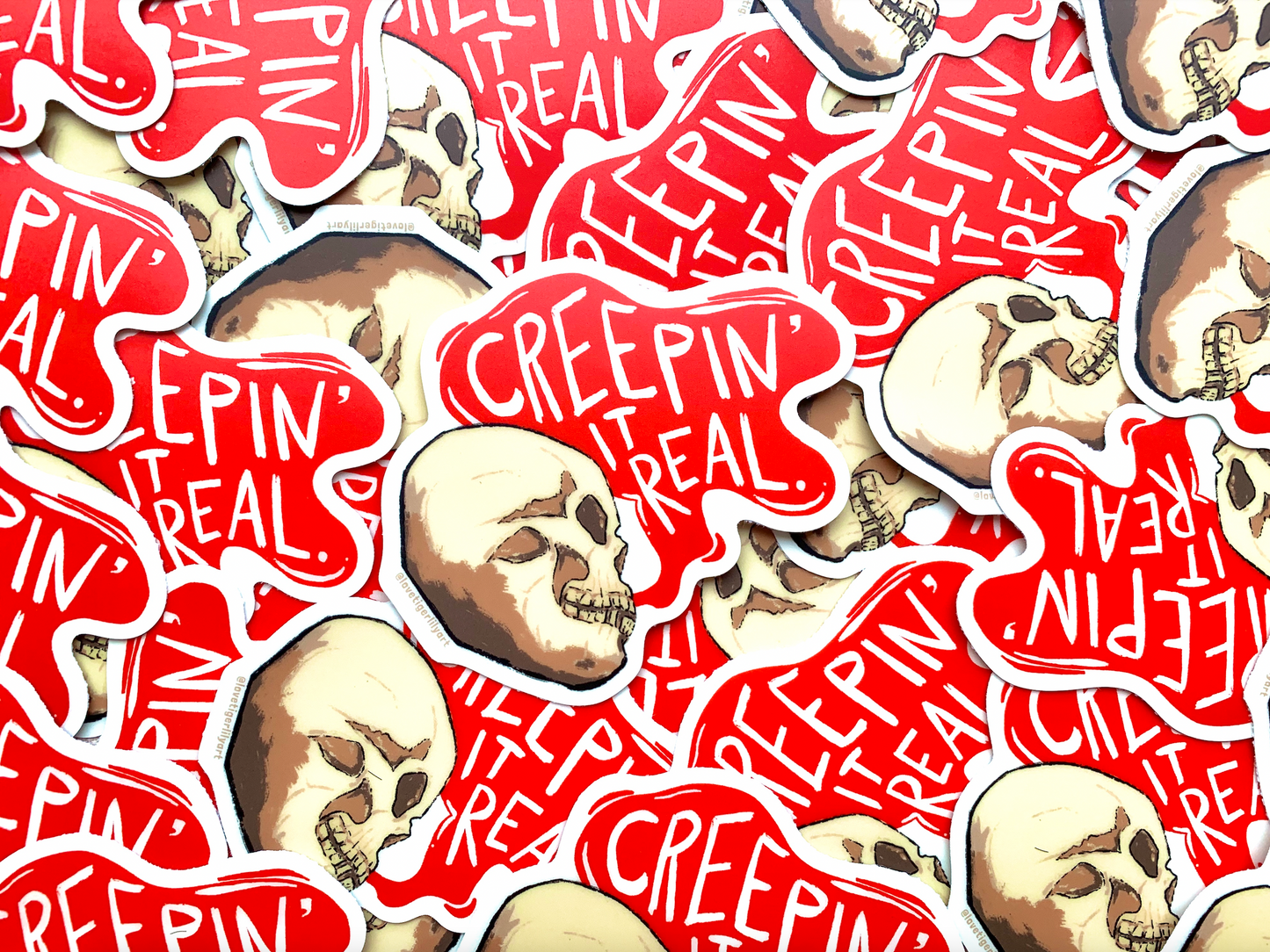 Multiple Glow in the Dark Creepin It Real stickers of an illustrated skull saying “Creepin It Real” in the daylight 